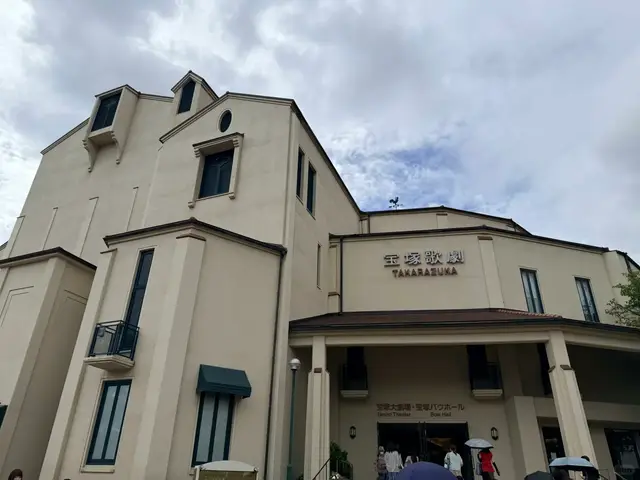 宝塚大剧场外观，「宝塚歌劇」字样和入口，观众正走进去